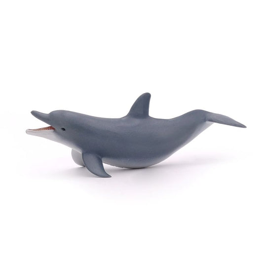 A toy figurine of a playing dolphin with a gray body, prominent fin, and a small hole on its head.