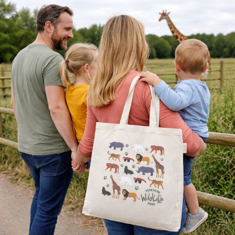 Family with a tote bag featuring animal illustrations in a natural setting