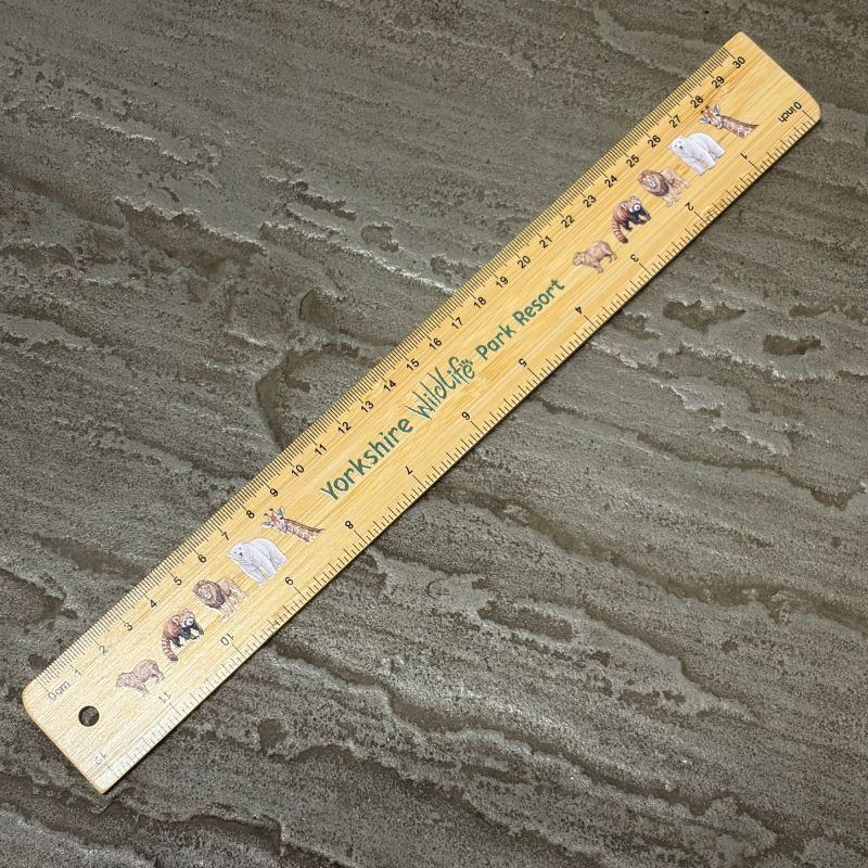 A bamboo ruler printed with 'Yorkshire Wildlife Park Resort' and featuring small animal illustrations, placed diagonally on a textured grey stone surface.