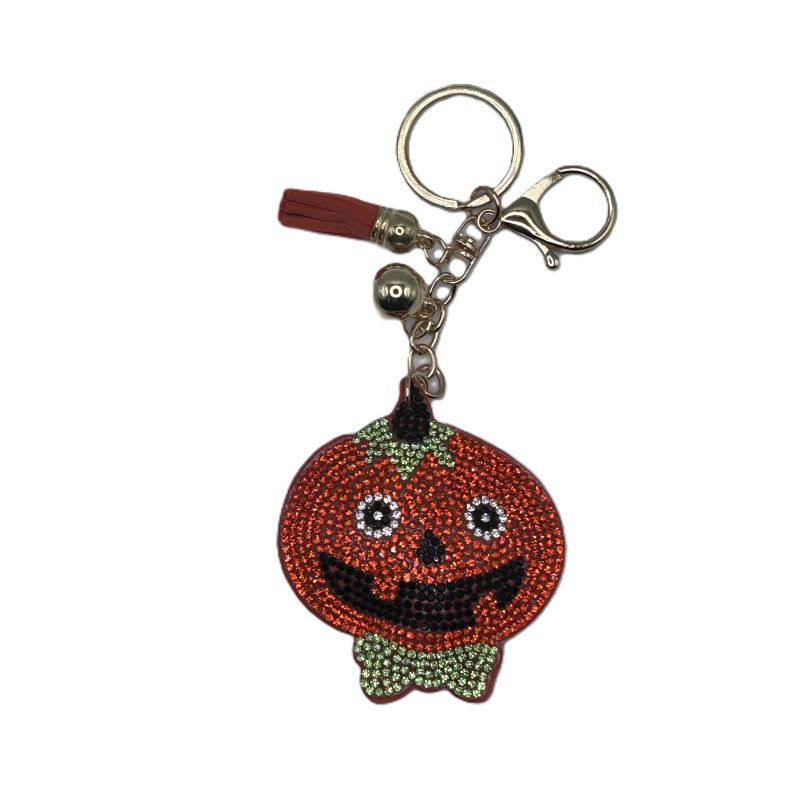 Pumpkin-shaped keychain with rhinestone details on a white background