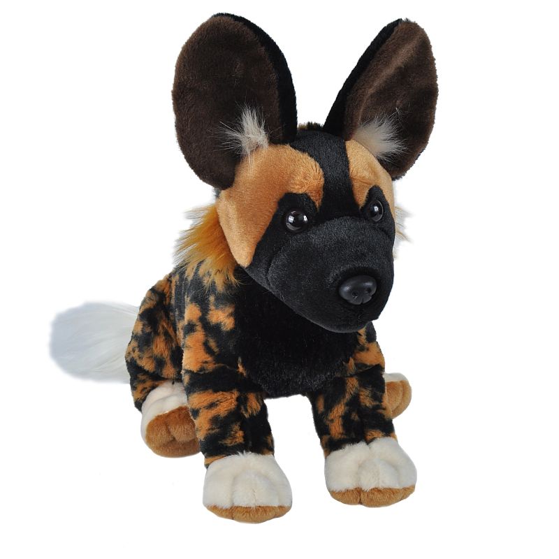 A large African wild dog plush toy with large upright ears, a black face and chest, tan and black mottled fur, and white paws, photographed on a plain white background.