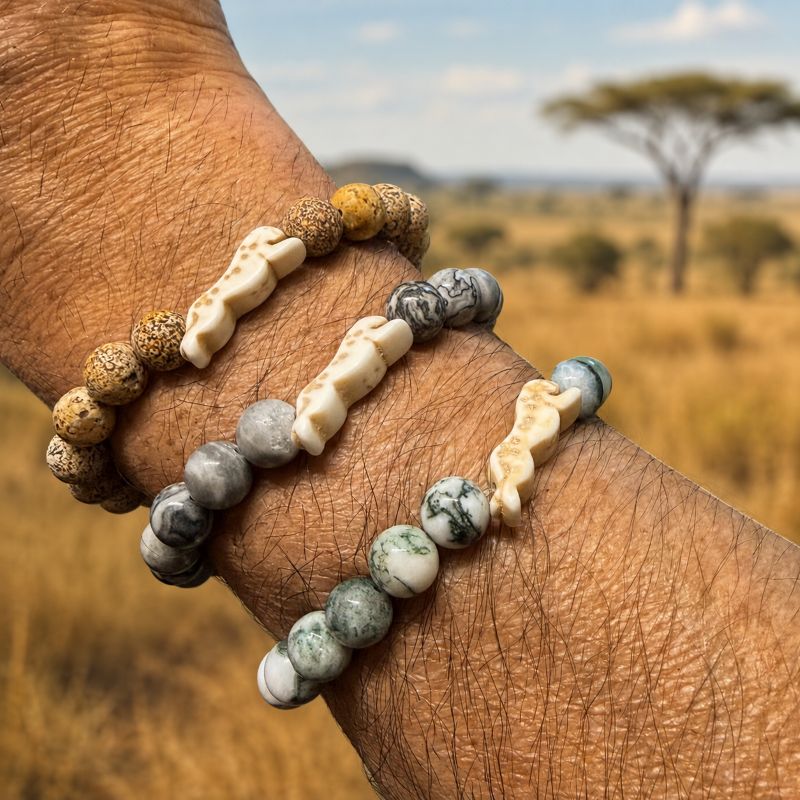 Hand wearing multiple beaded bracelets with cheetah charms and a natural landscape in the background