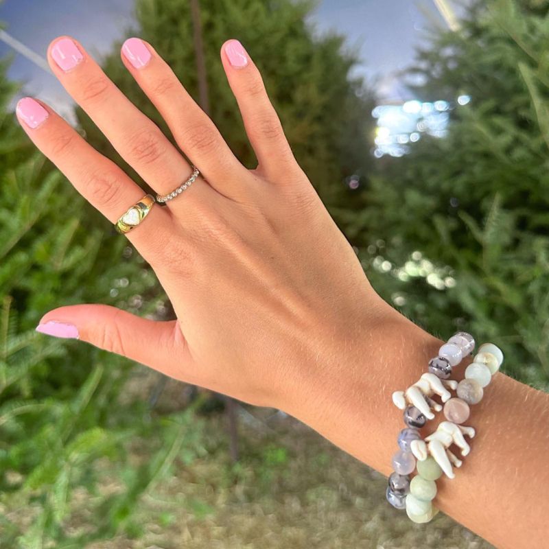 Hand wearing beaded fahlo bracelets with gorilla charm with a blurred green background