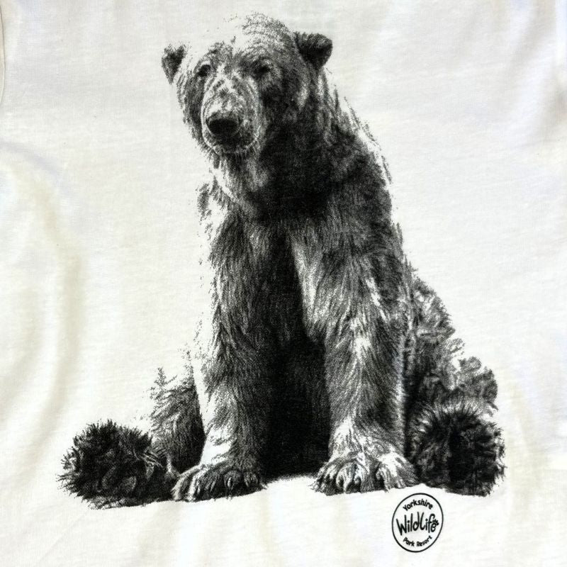 A close-up of a white T-shirt featuring a detailed black and white sketch print of a bear sitting down, with a circular 'WildKids' logo printed near the bottom right.