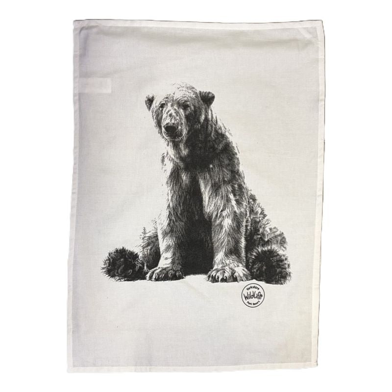 A rectangularwhite tea towel featuring a detailed black and white sketch of a bear sitting down, with a small circular yorshire wildlife park logo printed near the bottom right.
