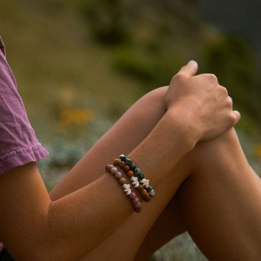 Person wearing beaded fahlo bracelets with koala charms and a blurred natural background
