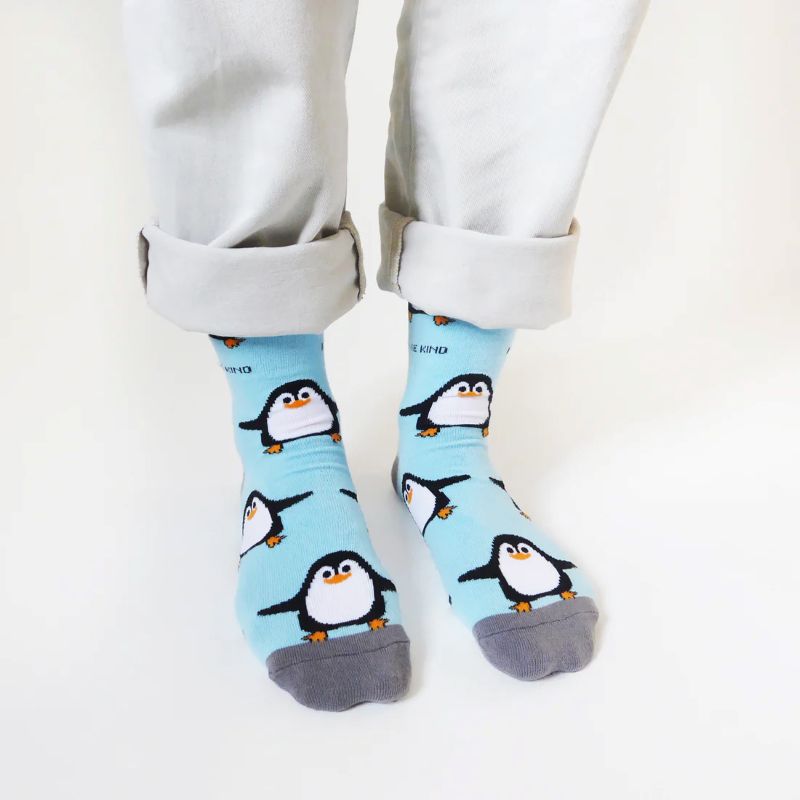 Person wearing light blue socks with penguin design on a white background