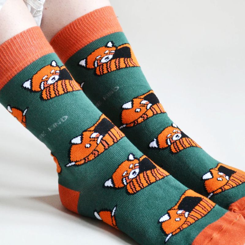 Green socks with orange panda pattern worn by a person on a white background