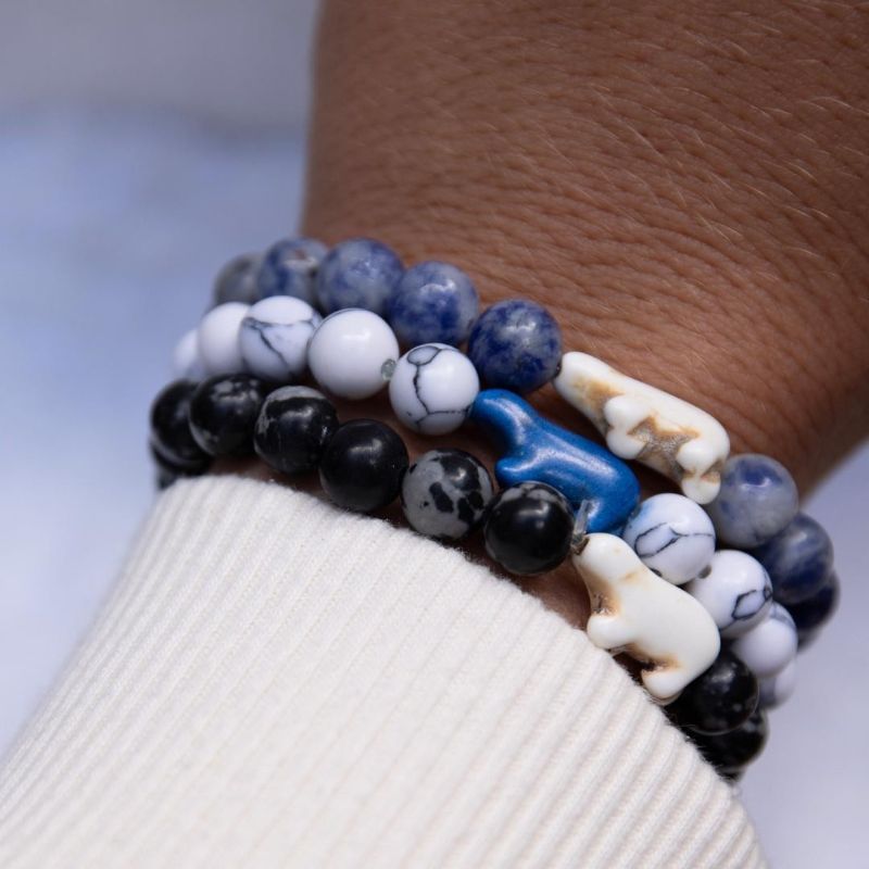 Stack of beaded bracelets with polar bear charms on a wrist with a blurred background