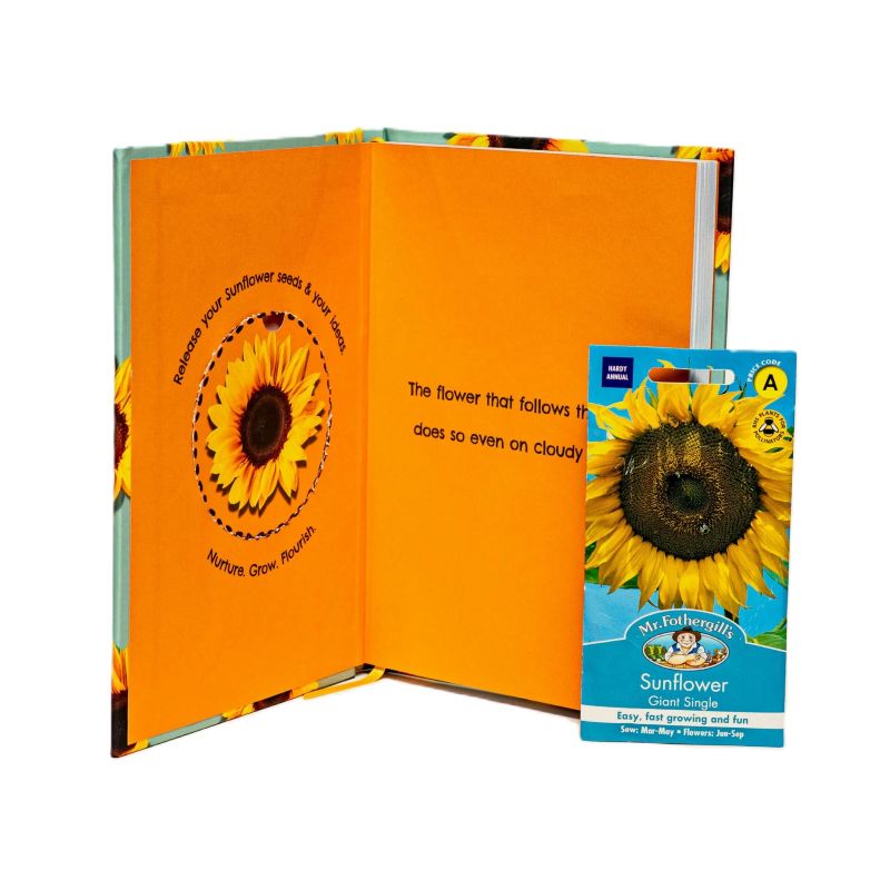 Open notebook with sunflower illustration and a small packet of sunflower seeds on a white background